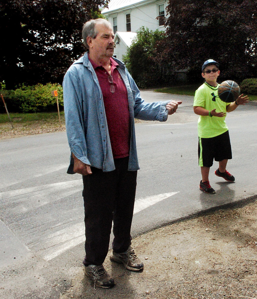 Norridgewock Upper Main Street resident Butch White and his grandson Parker stand near a speed hump Monday. White supports the raised pavement beside their home because it slows down drivers.