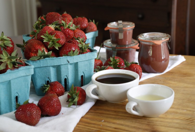 Ingredients for strawberry- maple butter are seen next to three jars of the finished product. 
