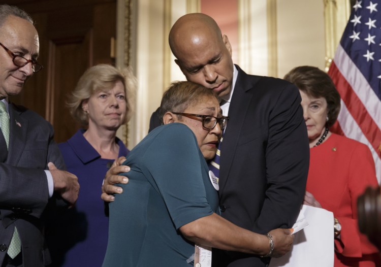 The Rev. Sharon Risher, a clinical trauma chaplain in Dallas who lost her mother, Ethel Lance, and two cousins in the racially-motivated shooting at a Church in Charleston, N.C., in 2015, is embraced by Sen. Cory Booker, D-N.J., during a news conference by Democratic senators calling for gun control legislation on Thursday Washington. From left are Sen. Charles Schumer, D-N.Y., Sen. Tammy Baldwin, D-Wis., and Sen. Dianne Feinstein, D-Calif.