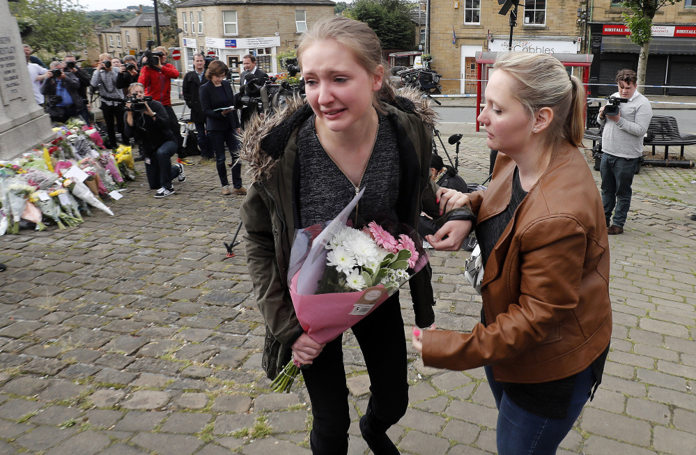 A young woman cries as she lays flowers in Birstall, West Yorkshire, England, Friday, June 17, 2016, the day after Labour MP Jo Cox was murdered in the street outside her constituency advice surgery.  (Peter Byrne/PA via AP) UNITED KINGDOM OUT NO SALES NO ARCHIVE