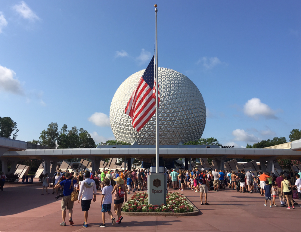 Tourists walk past a flag flown at half-mast in Epcot in Orlando on Monday. It remains to be seen if three tragedies will shake Orlando's status as the nation's top tourist destination, with 66 million visitors in 2015.