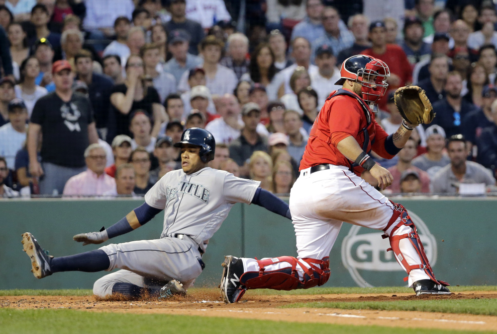 Seattle's Ketel Marte slides past Red Sox catcher Sandy Leon to score on a double by Franklin Gutierrez during the fourth inning of Friday's game at Fenway Park. The Mariners won, 8-4.