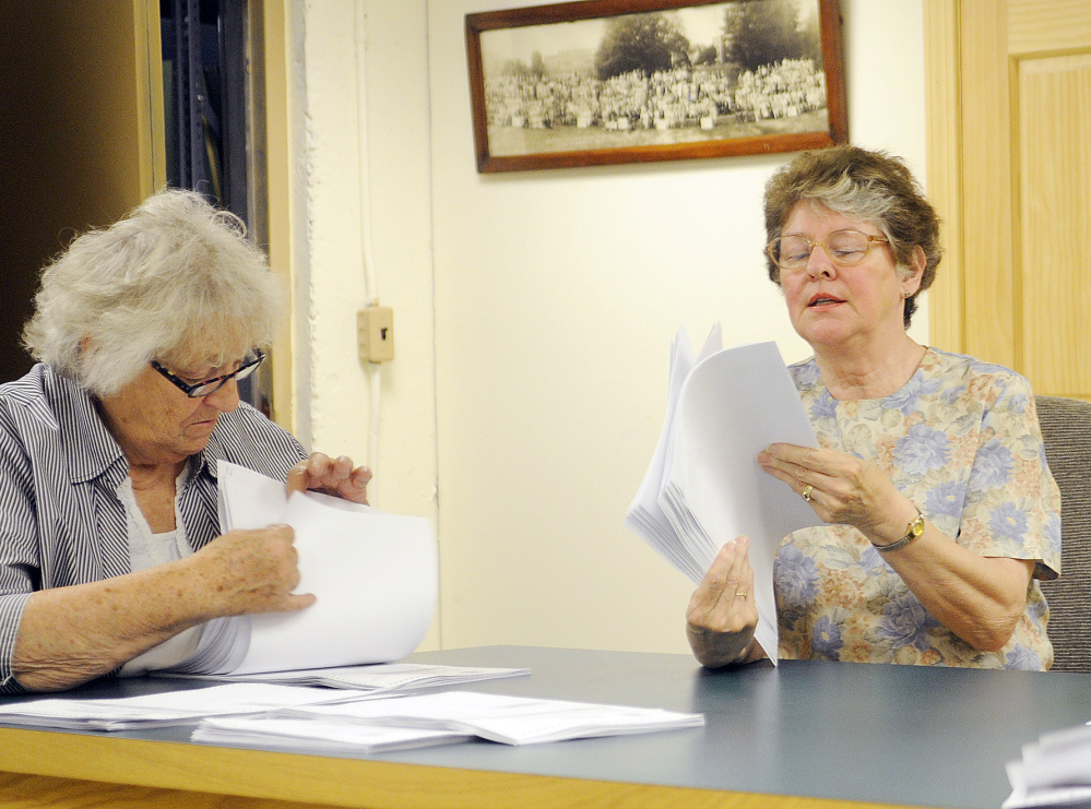 Esther Slattery, left, and Rayna Leibowitz inspect ballots Monday at the town office in Litchfield.