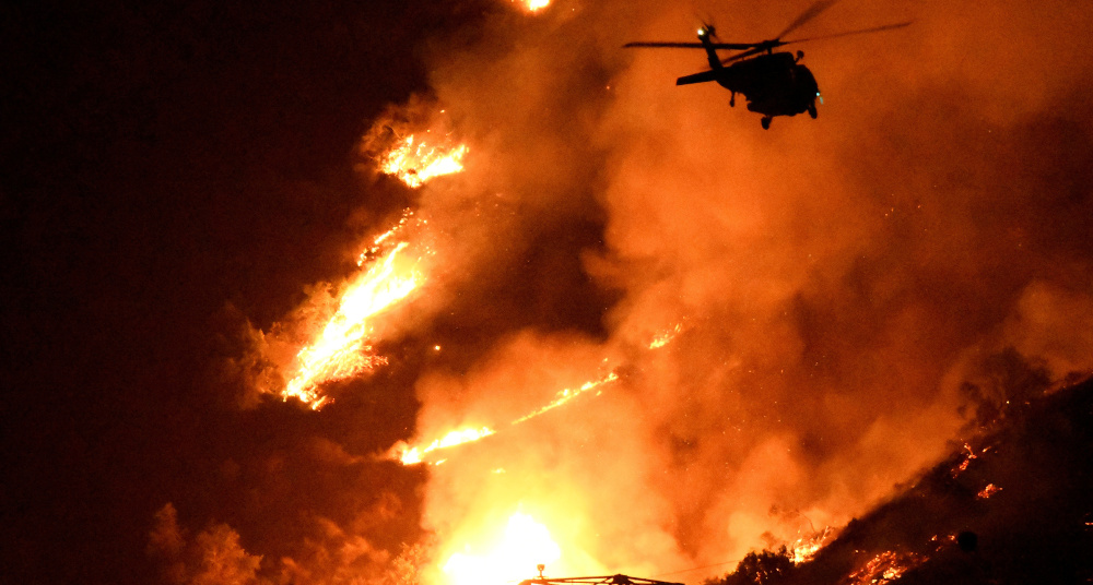 A Los Angeles County fire helicopter makes a nighttime water drop to slow the advance of a giant fire in the San Gabriel Mountains of Southern California on Monday. The wind had started to bring the fire down the mountains closer to homes.