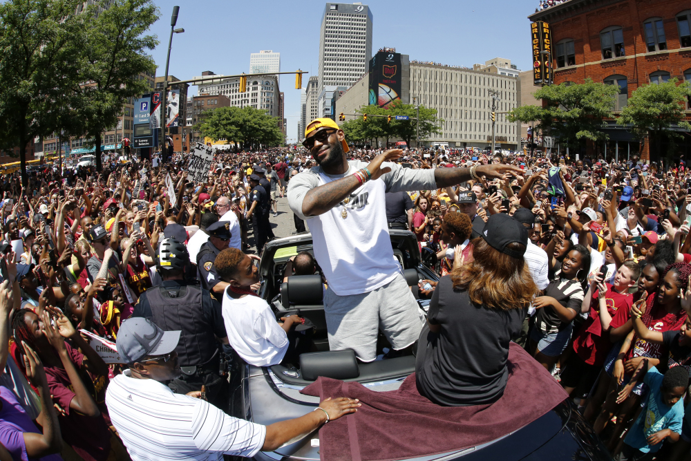 Cleveland Cavaliers' LeBron James stands in the back of a Rolls Royce as it makes its way through the crowd lining the parade route in downtown Cleveland on Wednesday, celebrating the basketball team's NBA championship.