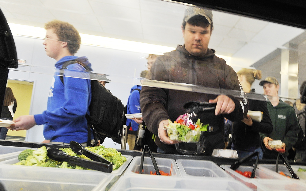 Senior Kenny Davis adds a tomato to his salad at Kennebunk High School's cafeteria in November 2014. Federal reforms implemented in 2012 have boosted U.S. K-12 students' fruit and vegetable consumption.