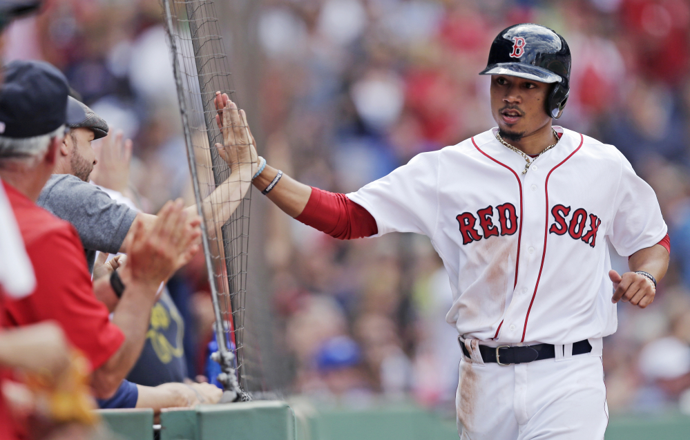 Boston's Mookie Betts, right, high-fives actor Donnie Wahlberg after scoring on a double by Dustin Pedroia in the fifth inning at Fenway Park on Thursday. Boston won the game in 10 innings, 8-7.