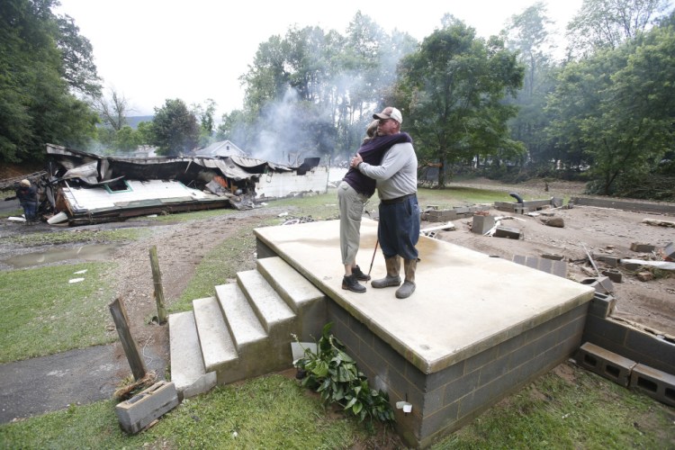 Jimmy Scott gets a hug from Anna May Watson as they clean up from severe flooding in White Sulphur Springs, W.Va., on Friday.