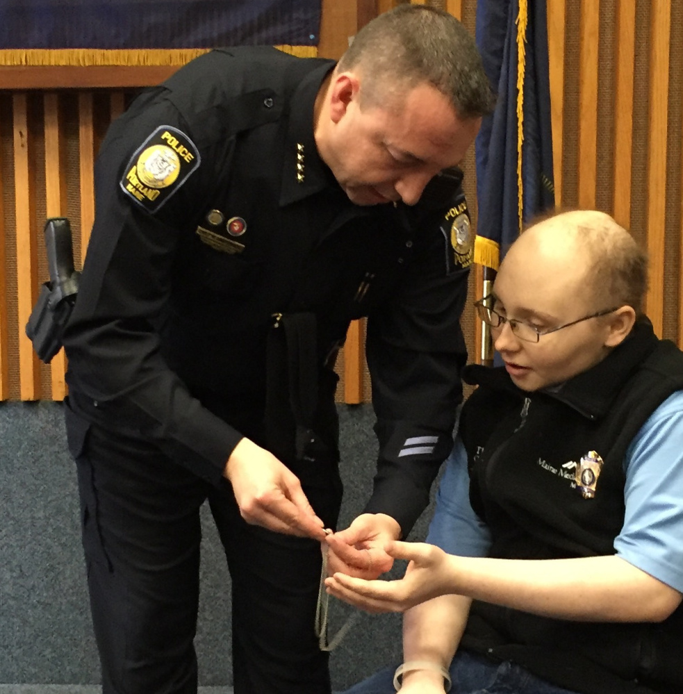 Portland Police Chief Michael Sauschuck hands Zachary Johnson a St. Christopher medal the chief had worn around his neck.