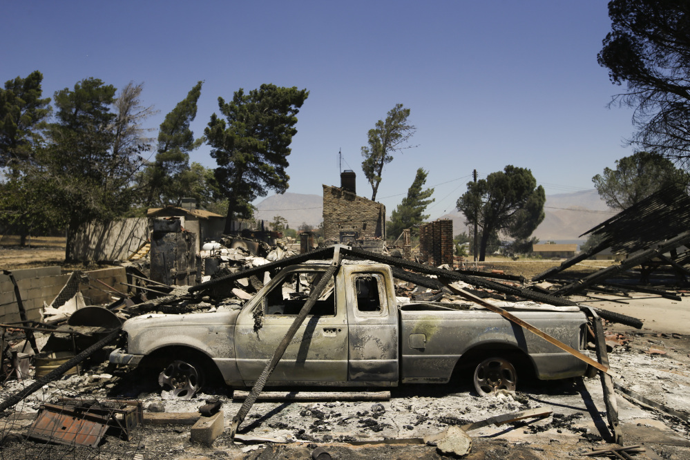 A pickup truck destroyed by fire sits on a burned-down property on Friday near Lake Isabella, Calif.