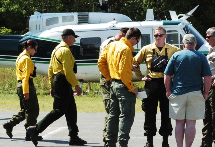 Maine Forest Service personnel consult at the Kingfield Fire Department on the status of the eight firefighters battling a fire on top of nearby Mount Abraham on Monday, with incident commander Shane Nichols, third from right, and Maine Forest Service Chief Ranger William Hamilton, right. Hamilton said the terrain and heat have been brutal for firefighters.