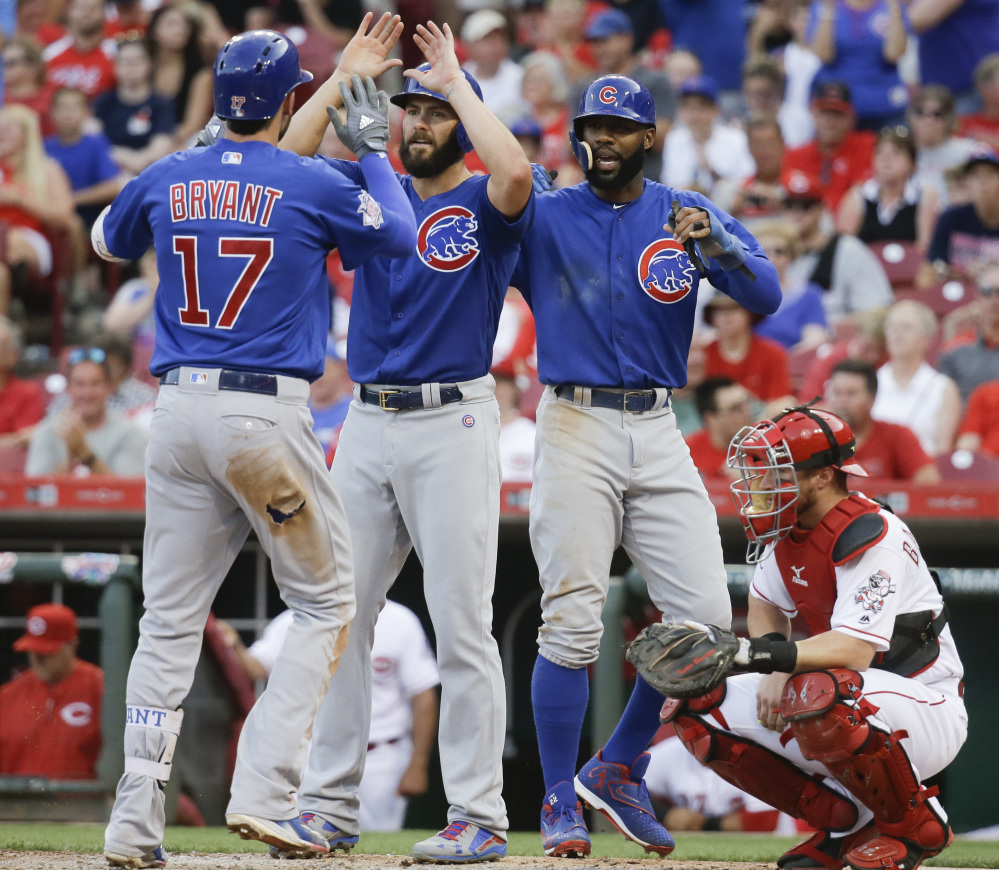 Kris Bryant, left, of the Chicago Cubs is greeted at the plate by teammates Jake Arrieta, center, and Jason Heyward after Bryant's three-run homer during an 11-8 win by the Cubs at Cincinnati on Monday. Bryant had three homers and two doubles in the game.