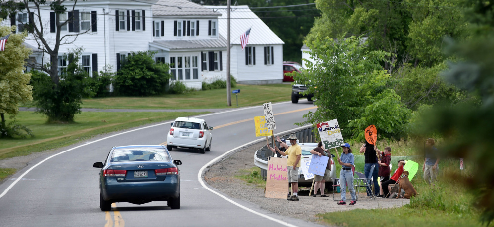 Demonstrators stand on Main Street in Vassalboro to oppose the planned removal of Masse Dam, which will drain Mill Pond, as part of an effort to restore alewife populations.