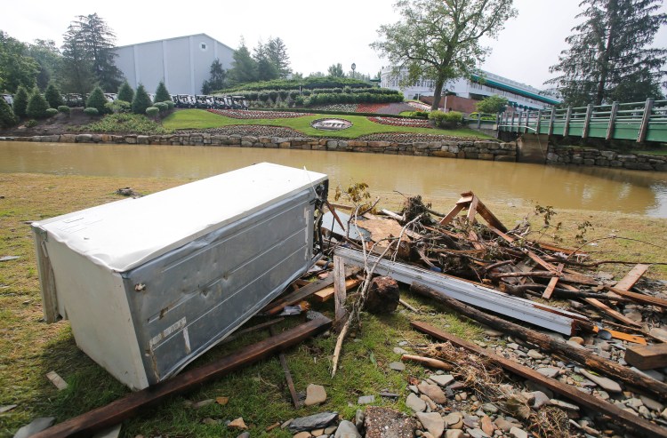 Debris is stacked up along Howard Creek in front of the first tee and the clubhouse as workers survey and begin the cleanup of the Old White Course on the property of the Greenbrier Resort in White Sulphur Springs, W. Va., Tuesday.    Associated Press Photo/Steve Helber
