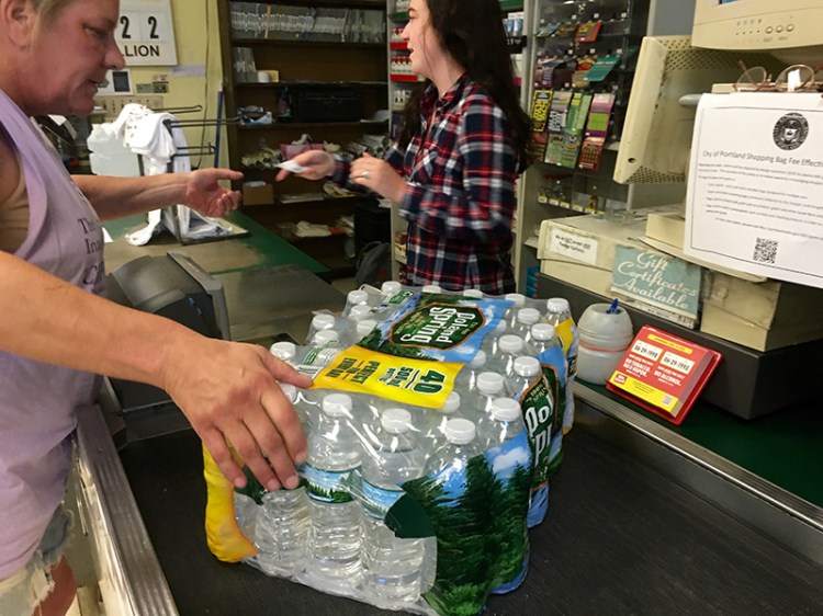 Hannigan's Island Market cashier Brook Tracy rings up a case of bottled water just minutes after opening at 8 a.m. Thursday. By 8:15, the small store was sold out.
