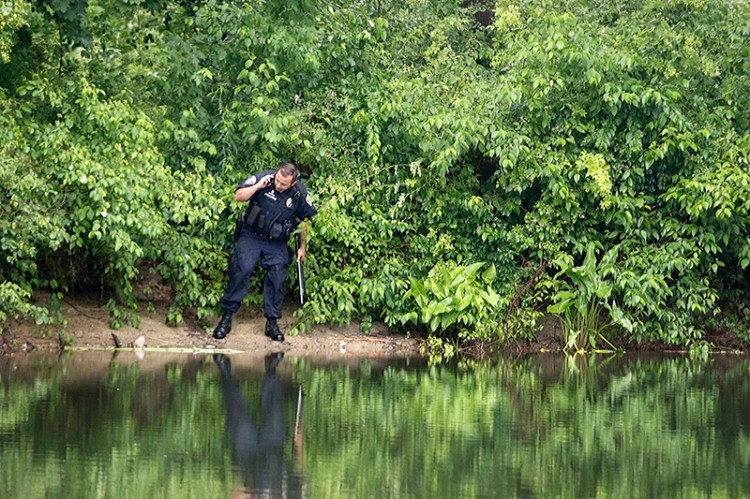 Officer Phil Robinson looks along the Presumpscot River in Westbrook after reports of a 10-foot-long snake seen eating a beaver.  