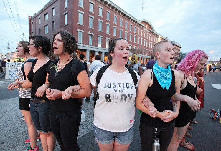 Chelsea Mancini, center, of Portland and others link arms while standing in the middle of Commercial Street during a July 15, 2016 protest by about 150 people who marched from Lincoln Park to Commercial Street, calling for changes for the Portland Police Department.