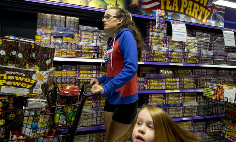 Hannah McIntyre of Bristol, Conn., pushes a shopping cart full of fireworks along an aisle in Phantom Fireworks in Scarborough on Friday while shopping with her family for an Independence Day celebration at Sebago Lake.