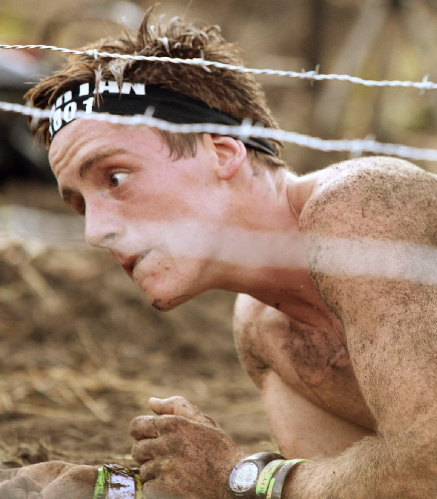 Isaac Douglass crawls under barbed wire during a Spartan race in Massachusetts in August 2015 – one of many such obstacles in the sport.