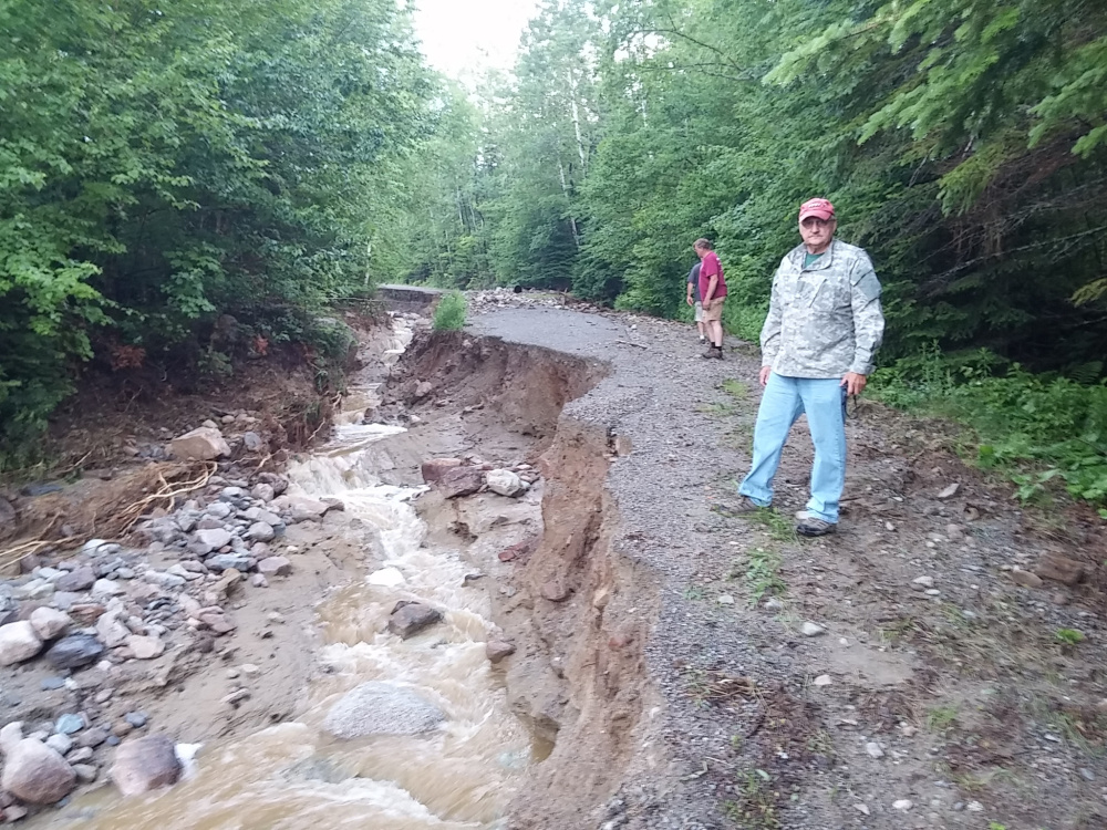 Rep. Larry Dunphy, of Embden, stands by a washed-out road Wednesday in northwestern Somerset County. Dunphy said he is trying to help secure financial help for residents of the area to fix the damage, which is estimated to cost nearly $1 million.