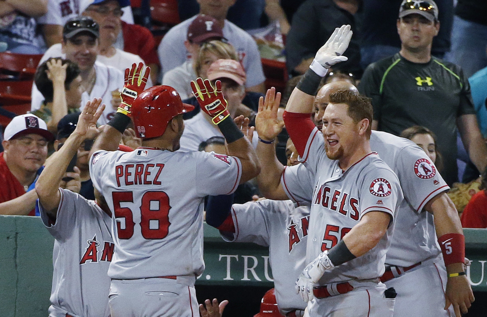 Carlos Perez of the Los Angeles Angels is welcomed by teammates Saturday night after hitting a two-run homer in the seventh inning of the 21-2 win over the Boston Red Sox.