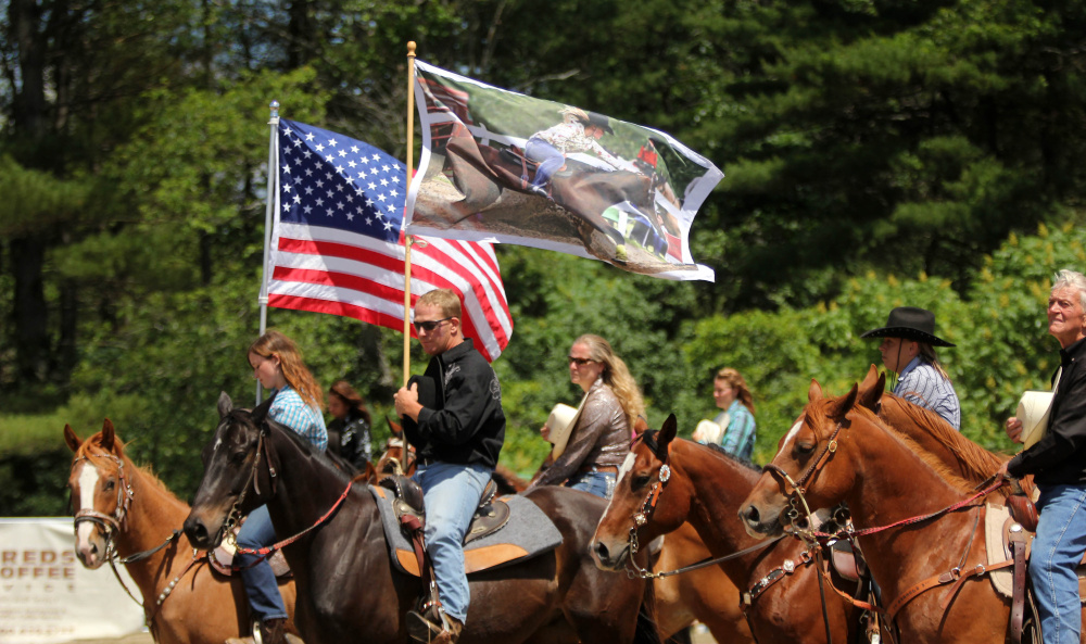 Hardy Cummings holds a flag with a photo of his late daughter before the start of the Halee Cummings Memorial Barrel Race in Sidney on Sunday.