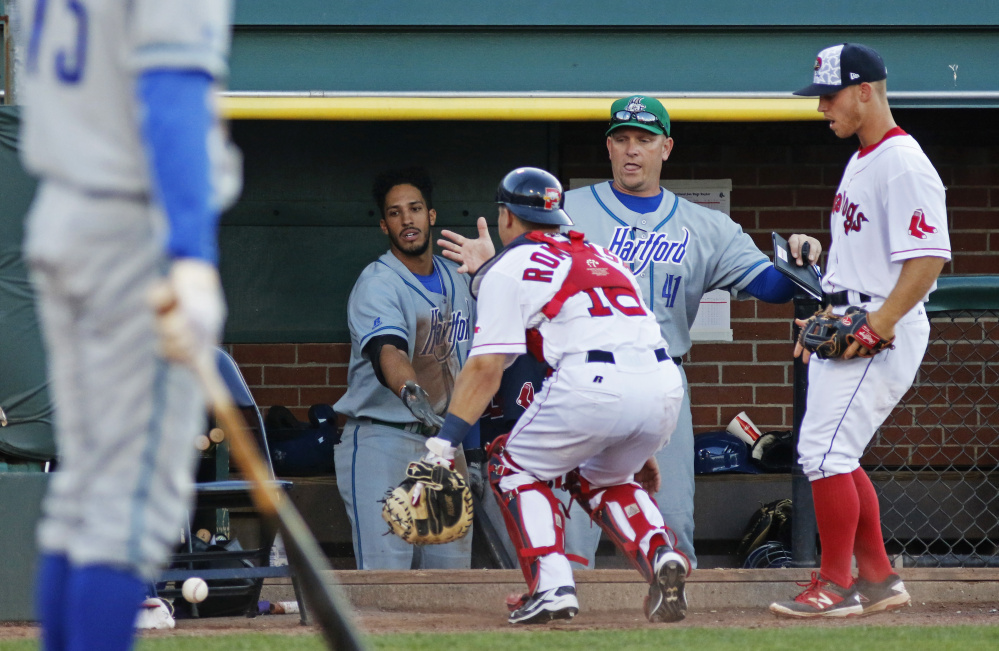 PORTLAND, ME - JULY 3: Hartford coach #41 Darin Everson is ready to catch Portland Sea Dogs catcher Jake Romanski as he chases a loose ball that tipped off his glove in the 7th inning vs. Hartford Yard Goats at Hadlock Field. Sea Dogs third baseman Sean Coyle looks on. (Photo by Jill Brady/Staff Photographer)