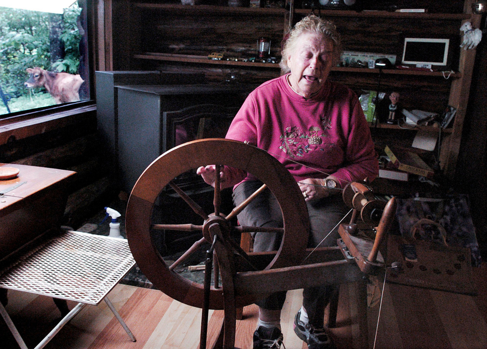 As a neighbor's wandering calf passes by the window, Mary Ann Anton begins to spin wool to make clothing at her home in West Athens last month. The Antons buried Mary Ann's husband, Carl, in the family burial ground.