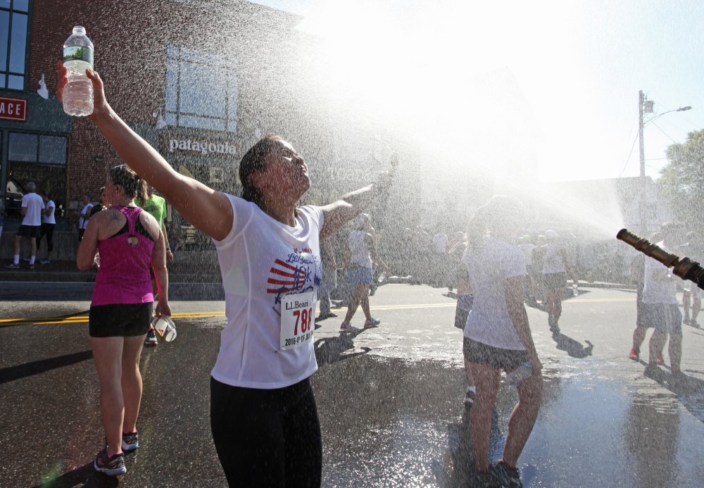 Amanda Mahaffey of Freeport cools down in a spray of mist after finishing the L.L. Bean 10K road race on Monday morning in Freeport. (Photo by Jill Brady/Staff Photographer)