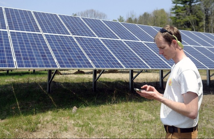 Hans Albee, an engineer at the ReVision Energy solar company in Portland, checks the Sky Ranch Solar Farm in the Kennebec County town of Wayne, which is owned by a group of community members. The Wayne project went online in May and can produce 49.6 kilowatts of power.