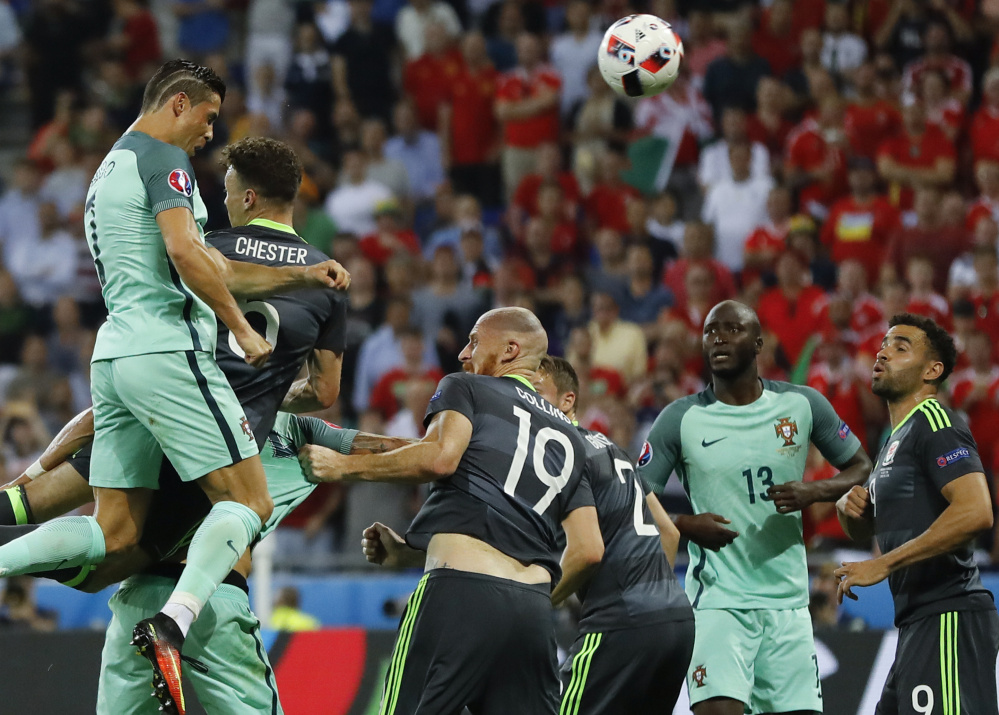 Cristiano Ronaldo, left, leaps over the defense to score on a header Wednesday – the first goal in a 2-0 victory for Portugal against Wales in the European Championship semifinals at Lyon, France.
