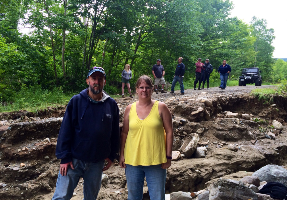 Norman and Lisa Lapointe, of Vassalboro, stand in the middle of No Road, where they own a camp, while surveying damage from last week's flash floods with other property owners Saturday. The Lapointes are able to access their property via a 45-minute detour over other roads and ATV trails and said they are not sure how the local road association will be able to pay for repairs.