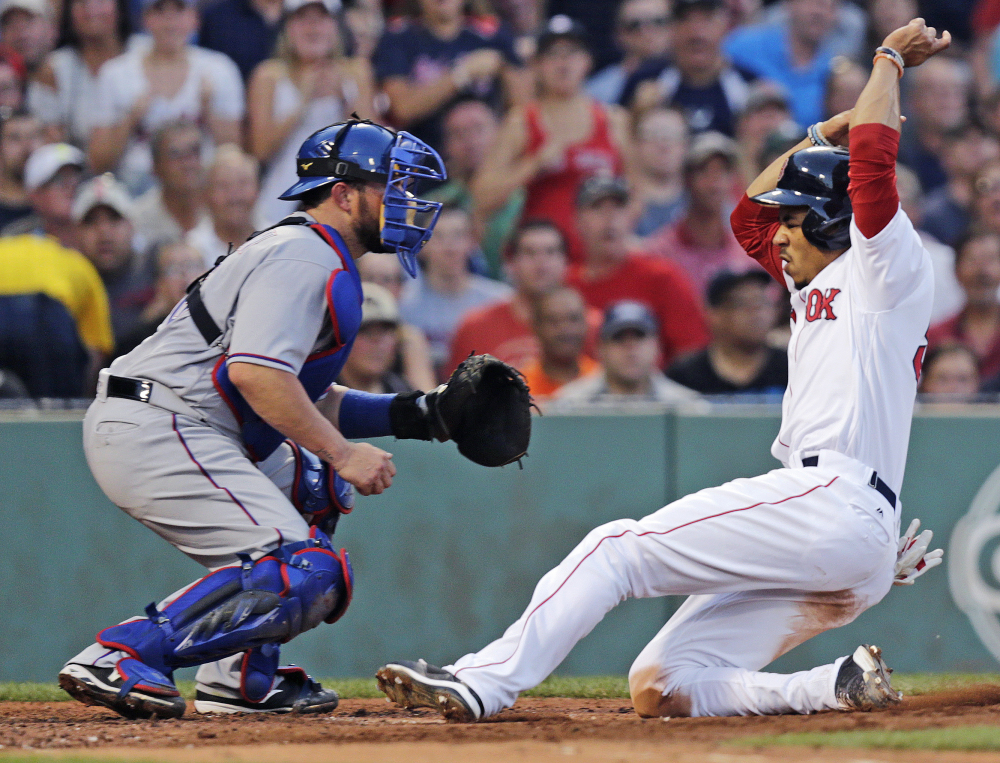 Mookie Betts beats the throw and slides home safely on a sacrifice fly by David Ortiz in the second inning. Boston blew the game open with five runs in the second.