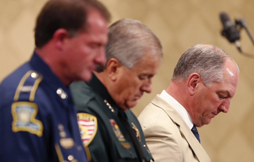 Louisiana Gov. John Bel Edwards, far right, bows his head in prayer with Baton Rouge Sheriff Sid J. Gautreaux III and Louisiana State Police Superintendent Colonel Michael D. Edmonson, left, at a prayer vigil Thursday for Alton Sterling, who was shot by Baton Rouge police on Tuesday.
