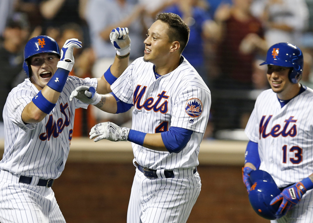 Brandon Nimmo, left, Wilmer Flores, center, and  Asdrubal Cabrera of the Mets celebrate after scoring on Flores' pinch-hit, three-run homer against the Nationals at New York on Thursday.