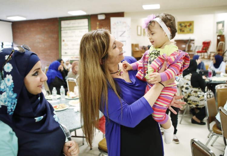 Zoe Sahloul, executive director of the New England Arab American Organization, center, greets 1-year-old Annabella Al Shaar as the child's mother, Oula Al Shaar, looks on during the Eid-al-Fitr celebration Saturday in Westbrook. Hundreds attended the event.