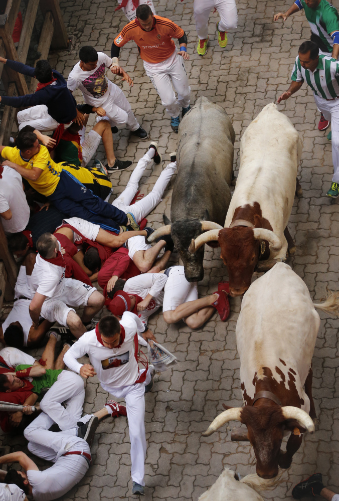 Revelers fall as they are chased by bulls running through the streets on Saturday in Pamplona, Spain, where more than 1,000 from around the world took part in the run.