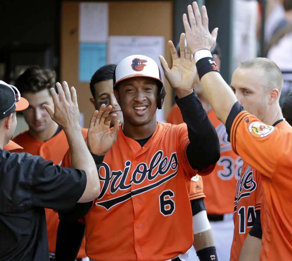 Baltimore's Jonathan Schoop high-fives teammates after scoring on a balk by Los Angeles Angels reliever Joe Smith in the seventh inning of Saturday's victory.