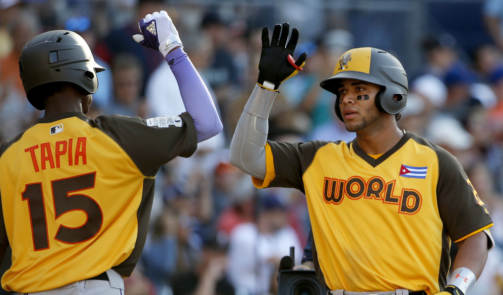 Yoan Moncada of the Boston Red Sox, right, gets congratulations from World teammate Raimel Tapia of the Colorado Rockies, after hitting a two-run homer run against the U.S. team in the eighth inning of the All-Star Futures Game in San Diego. The blast helped the World team win 11-3.