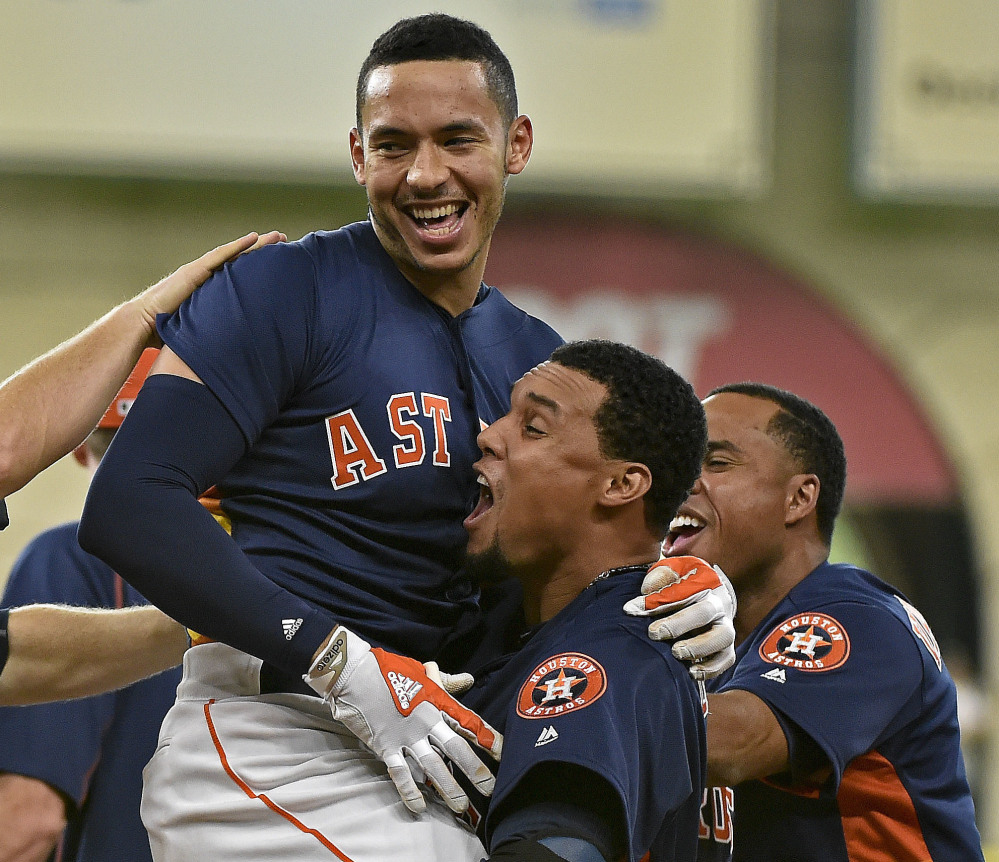 Astros shortstop Carlos Correa, top, celebrates his winning single with teammates on Sunday. Houston defeated Oakland 2-1 in 10 innings.