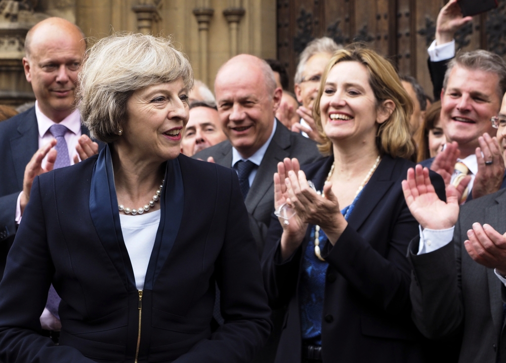 Britain Home Secretary Theresa May, left, is applauded by Conservative Party members of Parliament outside the Houses of Parliament in London on Monday.