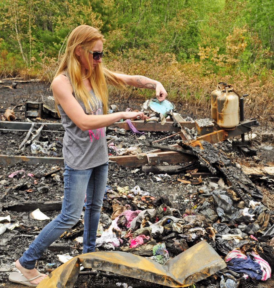Kristie Baker checks on items that survived the blaze on Thursday at the fire scene in Gardiner. Police arrested Joseph Manganella, 35, of Gardiner on Friday on a charge of arson related to the case.
