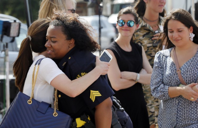 A well-wisher hugs Dallas police Sgt. Jamie Matthews, right, as they visit a makeshift memorial in front of the department's headquarters Monday. Police Chief David Brown said that he is considering requiring everyone on the force to seek counseling in the coming months.