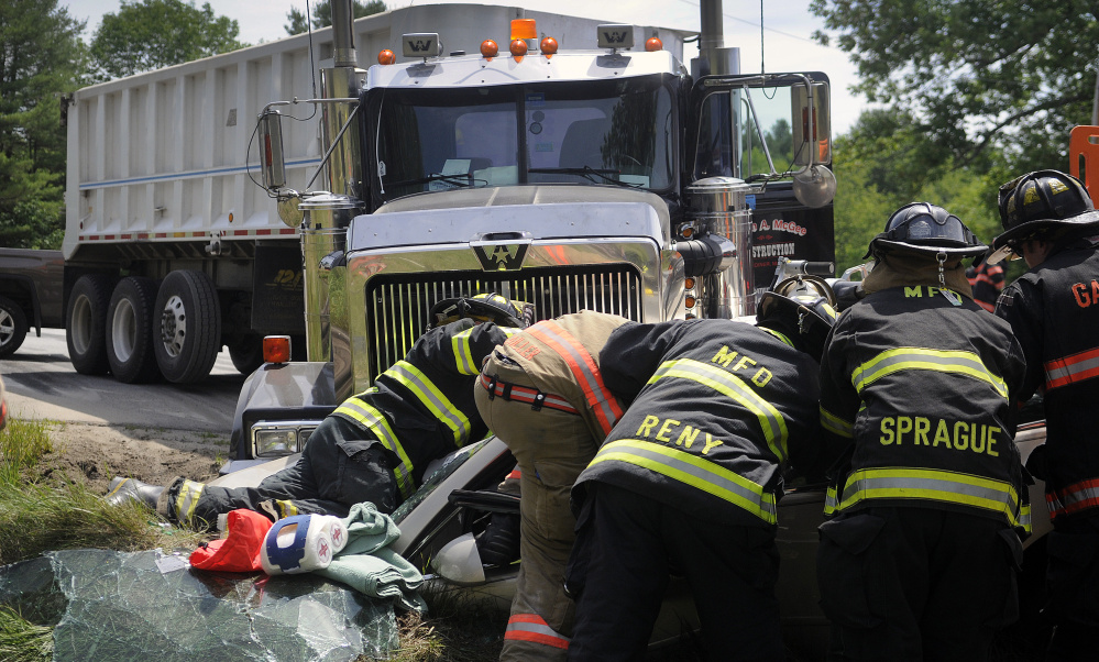 Firefighters extricate two people who were trapped Tuesday in a car that collided with a tractor-trailer on Route 126 in Litchfield. The driver of the truck was uninjured.