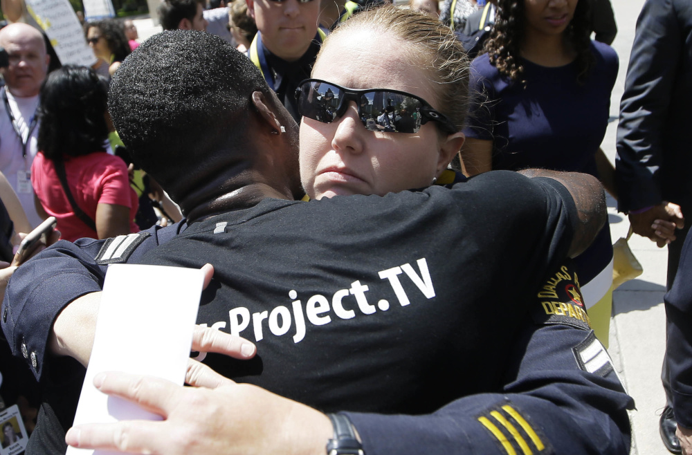 A Dallas police officer is hugged after a memorial service for fallen fellow officers Tuesday, in which President Obama declared that a week of deeply troubling violence has seemed to expose "the deepest fault lines of our democracy." But he insisted the nation is not as divided as it seems and called on Americans to find common ground in support of racial equity and justice.