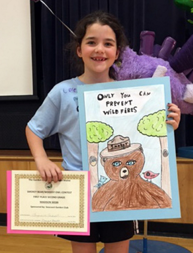 Wells Elementary School student Madison Webb poses with her award-winning poster "Only You Can Prevent Wildfires."