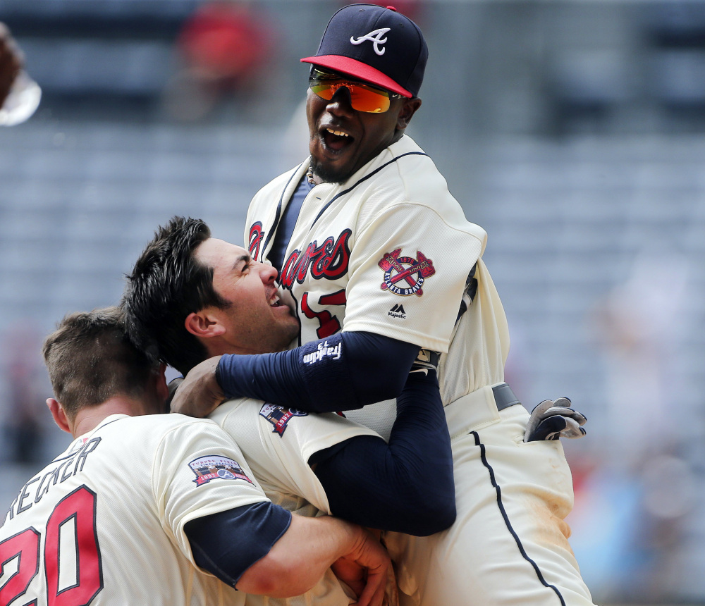 Atlanta Braves' Chase d'Arnaud, center, celebrates with Adonis Garcia, right, and Anthony Recker after driving in the winning run with a base hit in the in the ninth inning of a baseball game against the Colorado Rockies, Sunday, July 17, 2016, in Atlanta. (Associated Press/John Bazemore)
