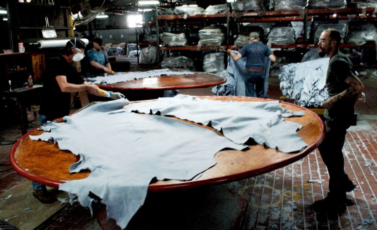 Employees at Tasman Leather work at a station at the Hartland tannery in 2016. Today's guest columnist argues that the impact of globalization on industries such as tanning means that Maine's rural people often have more in common with immigrants from poor regions than they do with owners of the corporate chain stores where they shop.