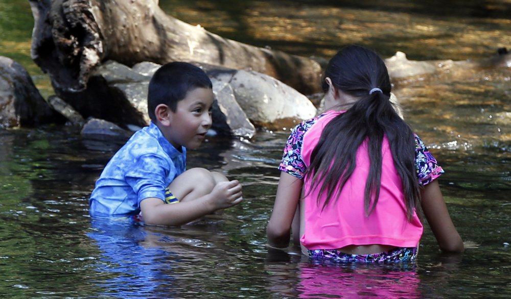Two children cool off in Minnehaha Creek as oppressive heat and tropical humidity move the heat index to over 100 degrees Wednesday in Minneapolis.