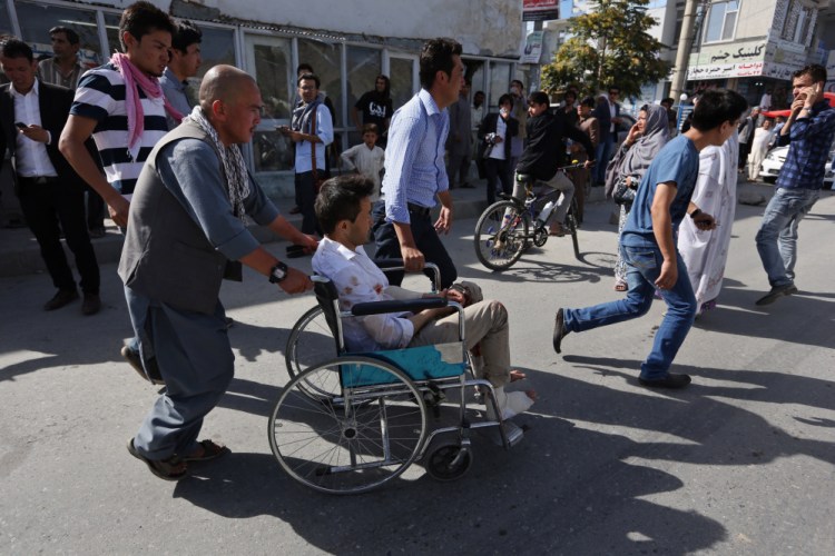 Afghans help an injured man at a hospital after an explosion struck a protest march in Kabul, Afghanistan, on Saturday.